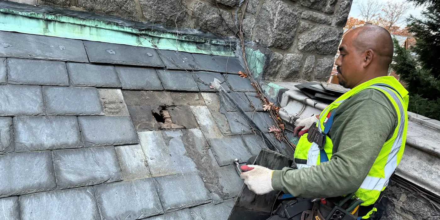 Usource roofer repairing slate and flashing on the church roof