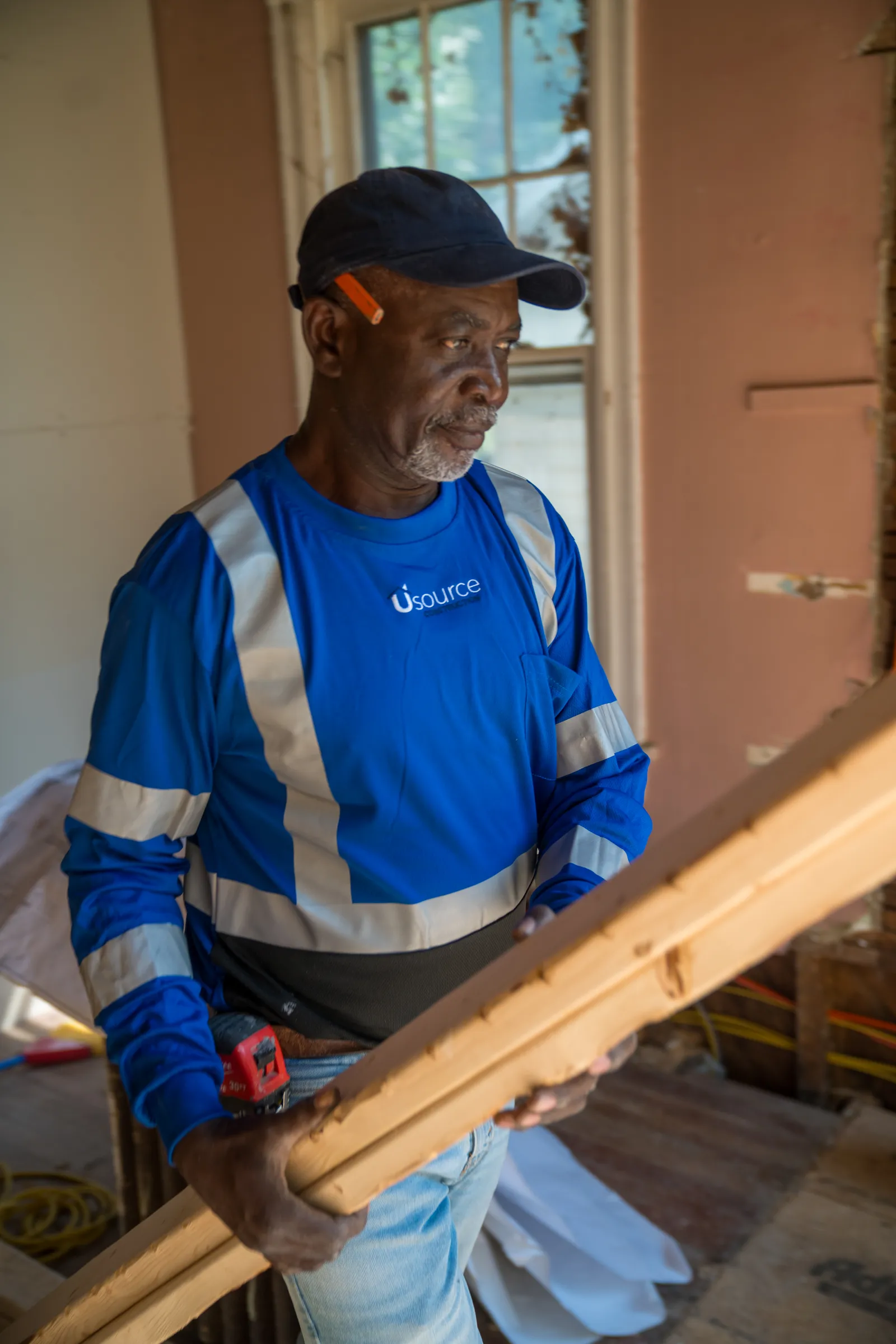 Usource carpenter carrying framing lumber
