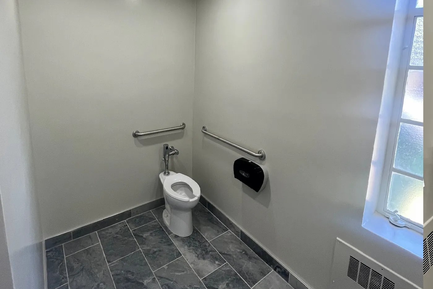 Renovated restroom with grab bars and slate flooring