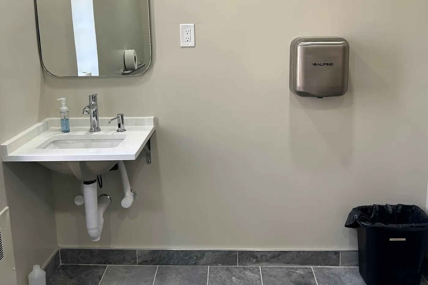 Sink, mirror and hand dryer in a renovated Trinity restroom